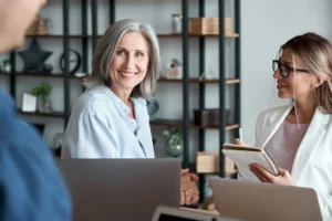 Smiling senior woman receiving Medicare advice from a professional broker during consultation