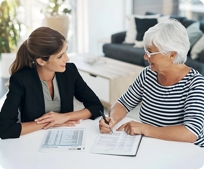 A young professional woman assists an elderly woman with her documents.