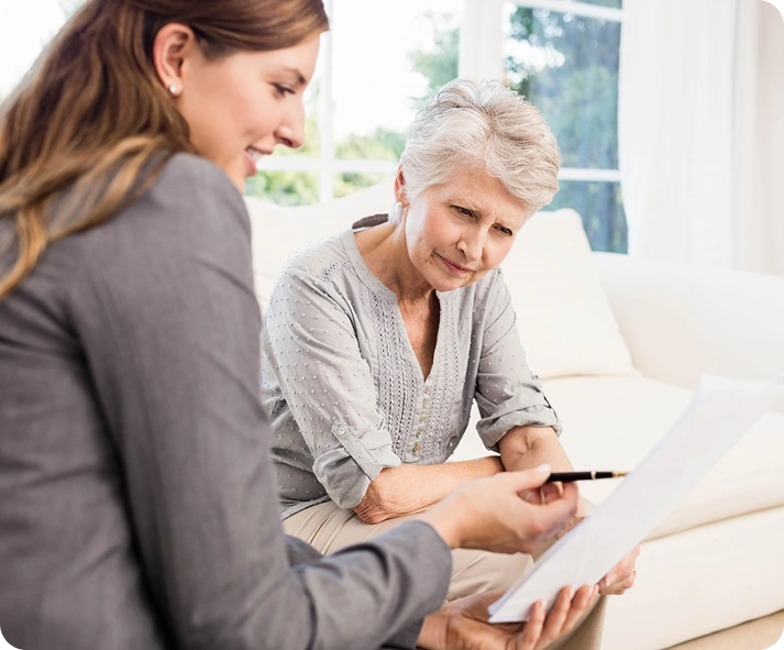 Two women, one younger and one older, are engaged in conversation while sitting together on a couch.
