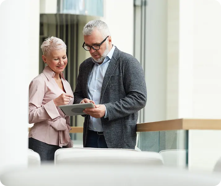 Two coworkers discussing content on a tablet in an office.