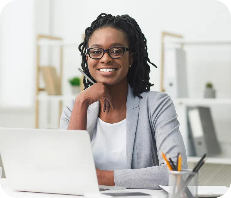Woman smiling while working on a laptop in an office.