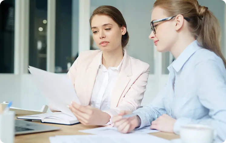 Two women reviewing documents together in an office.